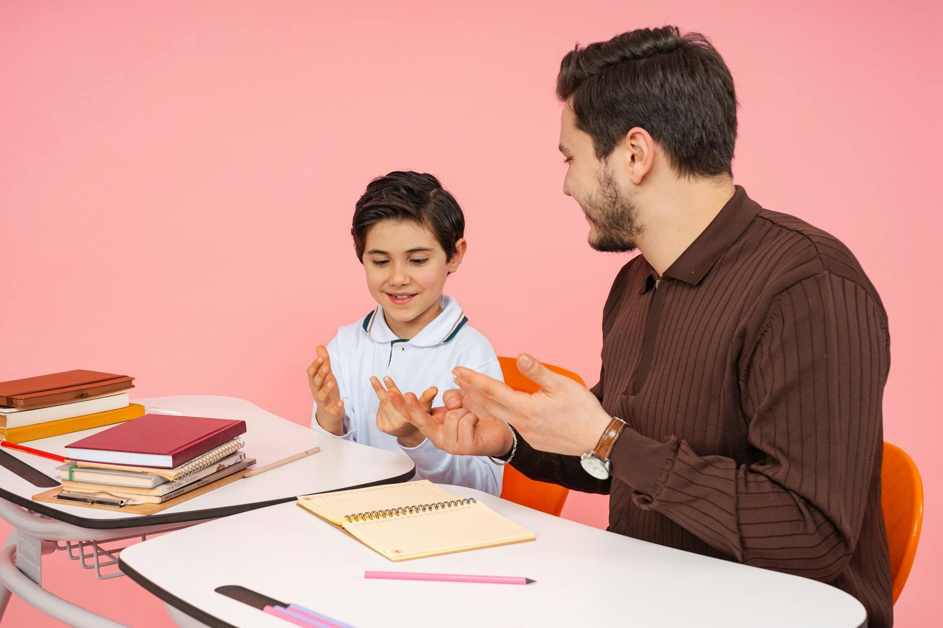Nauczyciel i uczeń rozmawiają przy ławce w klasie