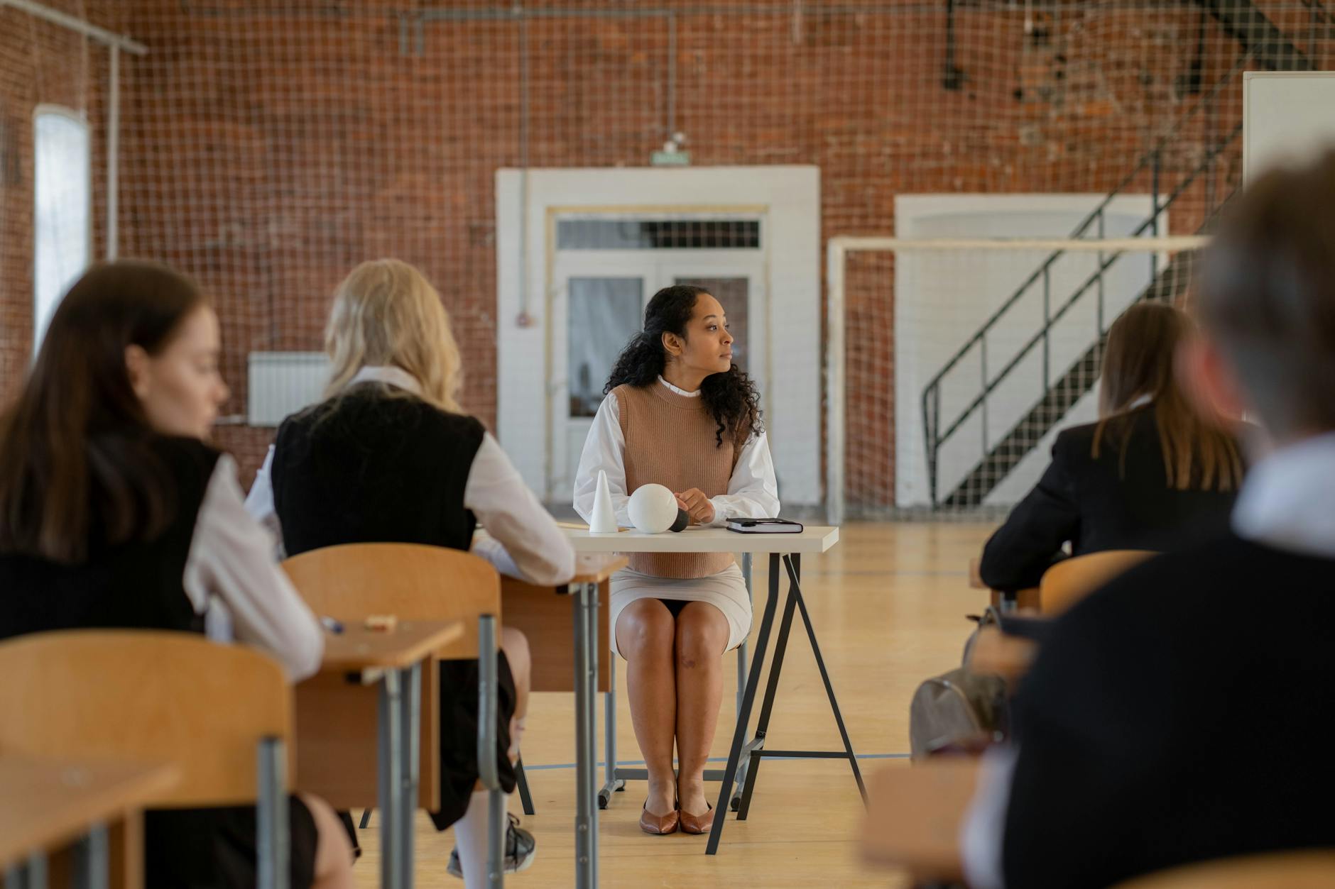 Nauczyciel przy biurku prowadzi lekcję w sali gimnastycznej