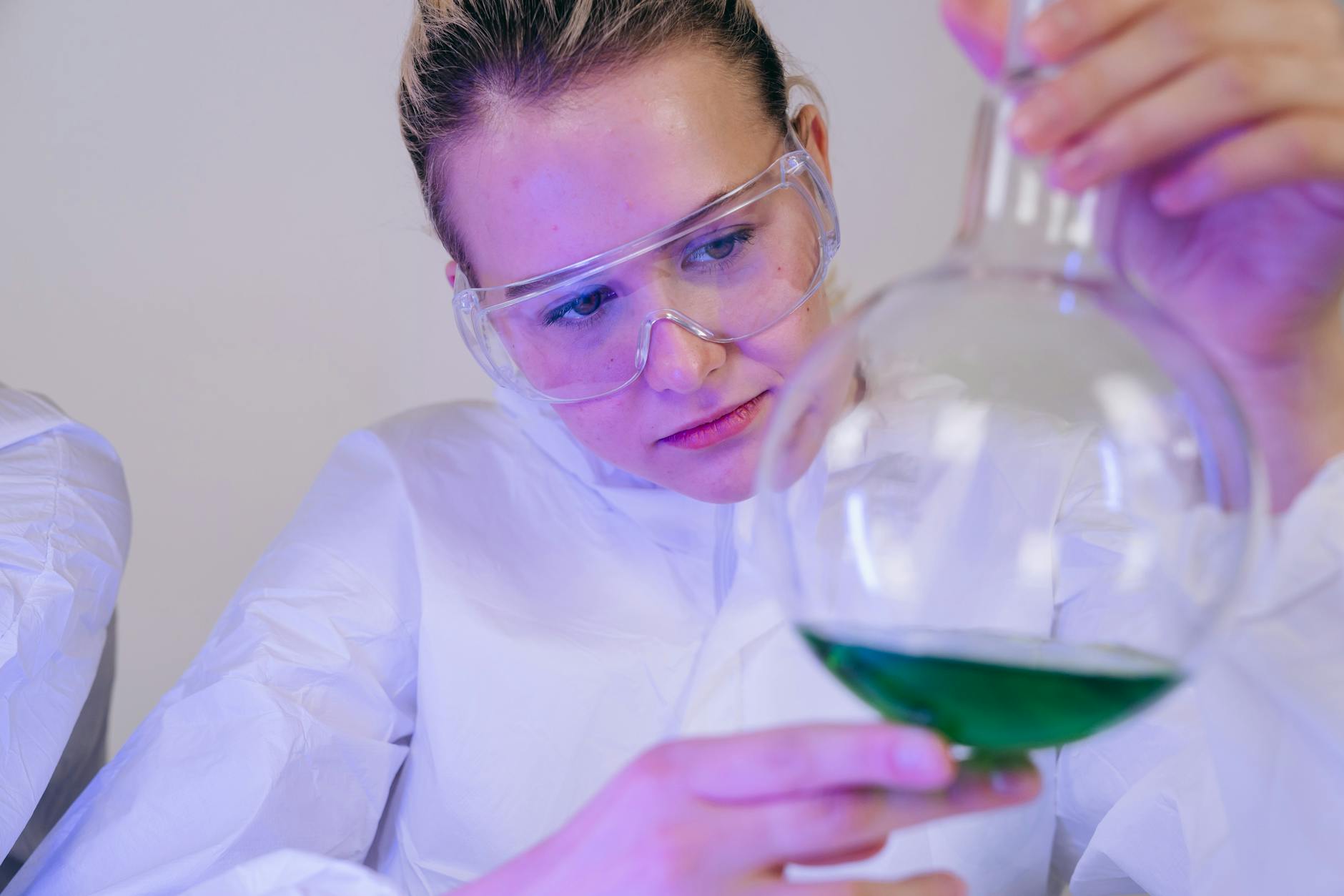 Naukowczyni w laboratorium bada zielony roztwór w probówce