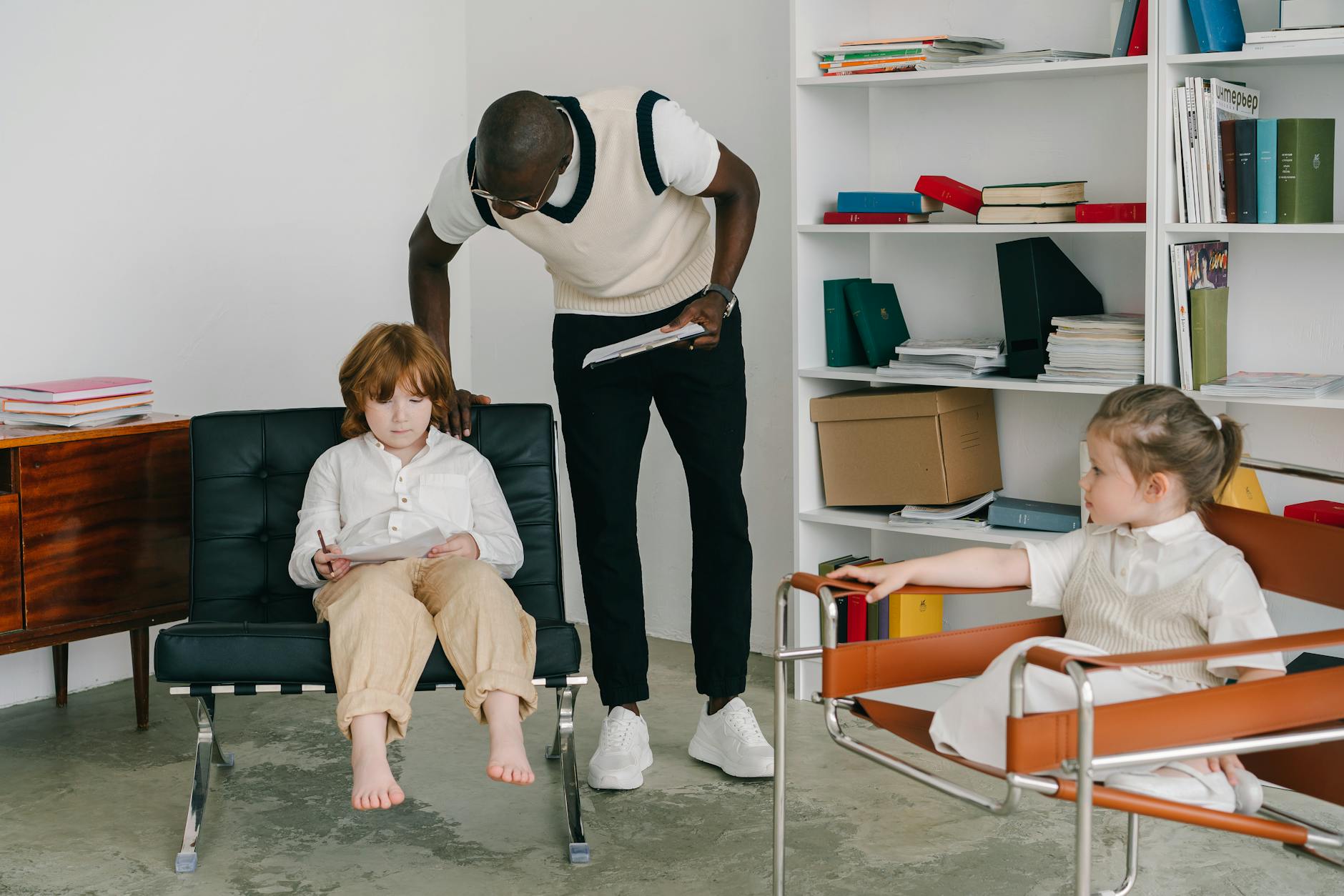 Terapeutka rozmawia z dziećmi w jasnym gabinecie terapeutycznym