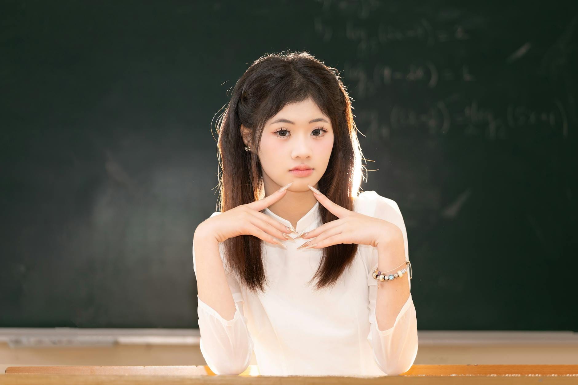 Zamyslona uczennica siedzi w klasie na tle szkolnej tablicy