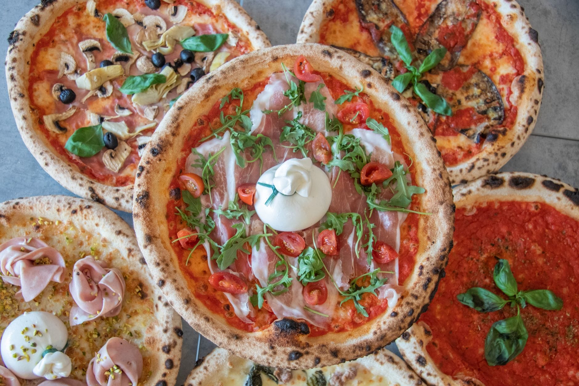 Różne pizze z szynką, serem i warzywami widziane z góry