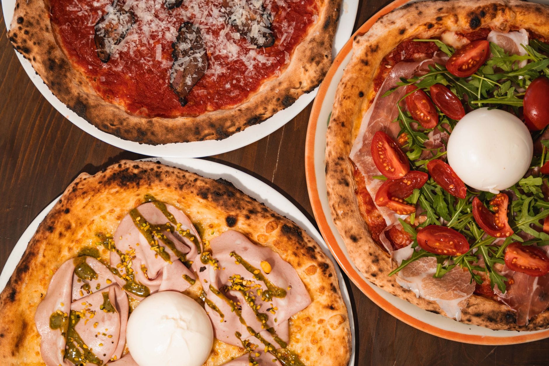 Różne włoskie pizze z dodatkami na stole w klimatycznej pizzerii