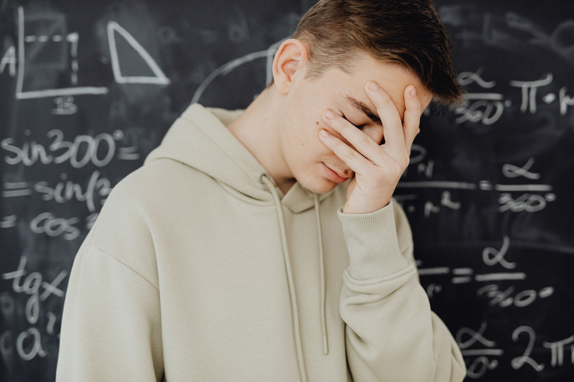 Przytłoczony uczeń przy tablicy pełnej działań matematycznych